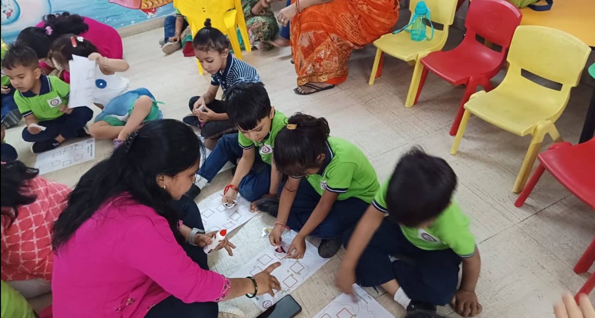 Children sitting on the floor working on a worksheet activity with their teacher