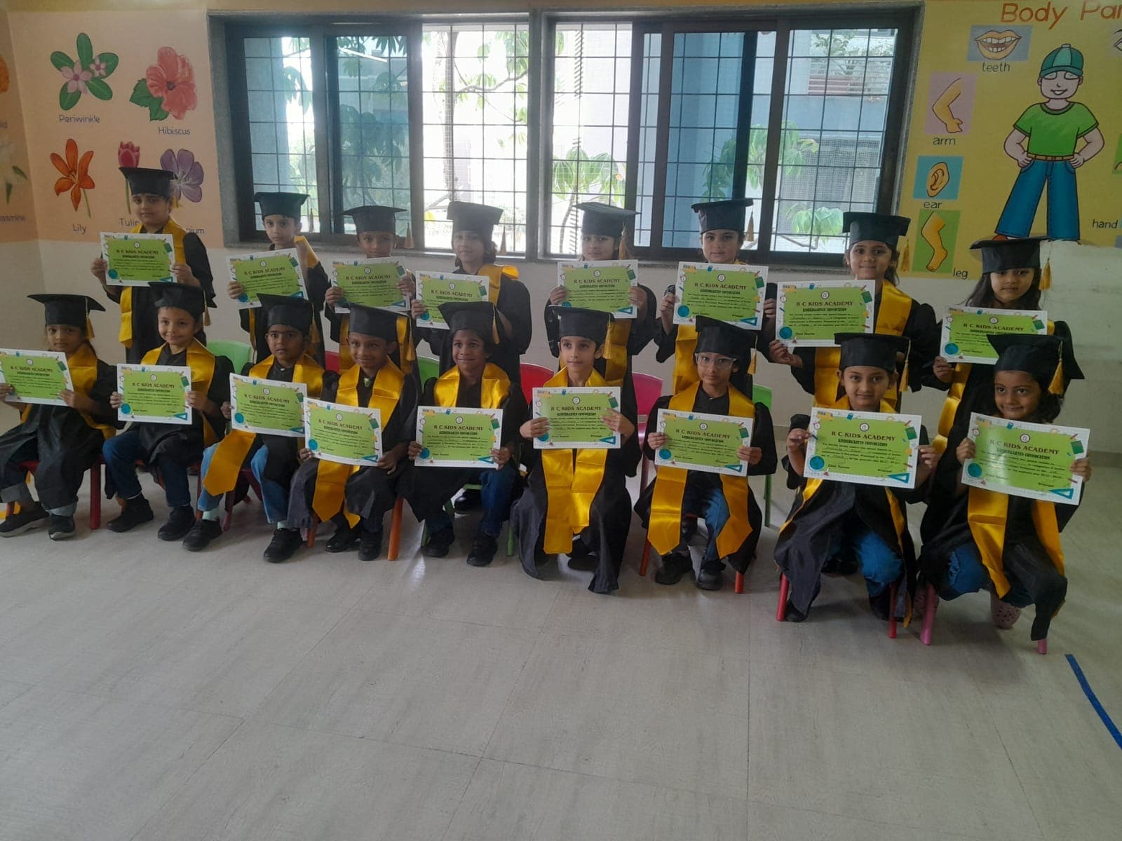 Children in graduation caps and gowns holding RC Kids Academy kindergarten convocation certificates
