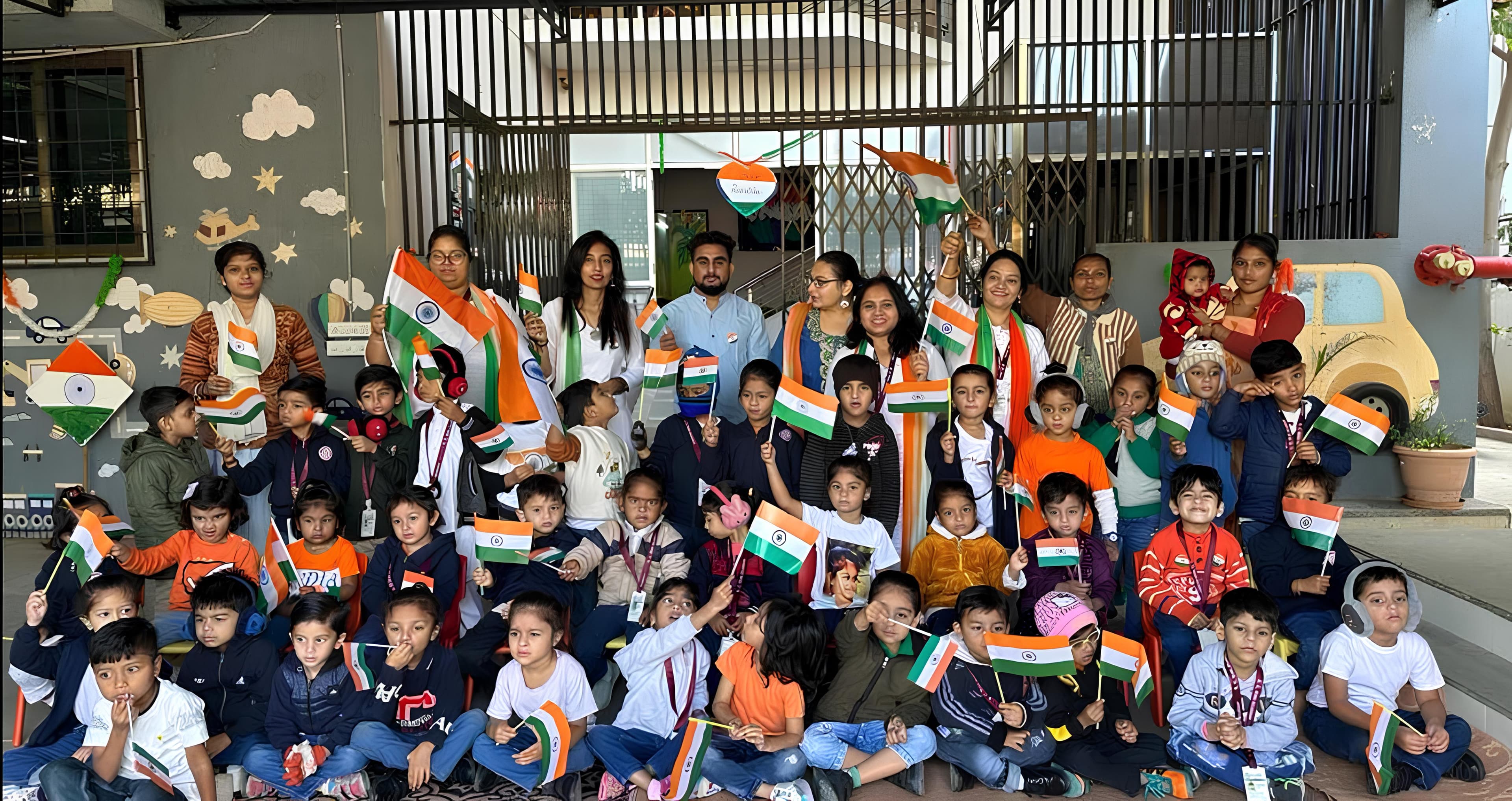 Children and staff holding Indian flags outside the school building